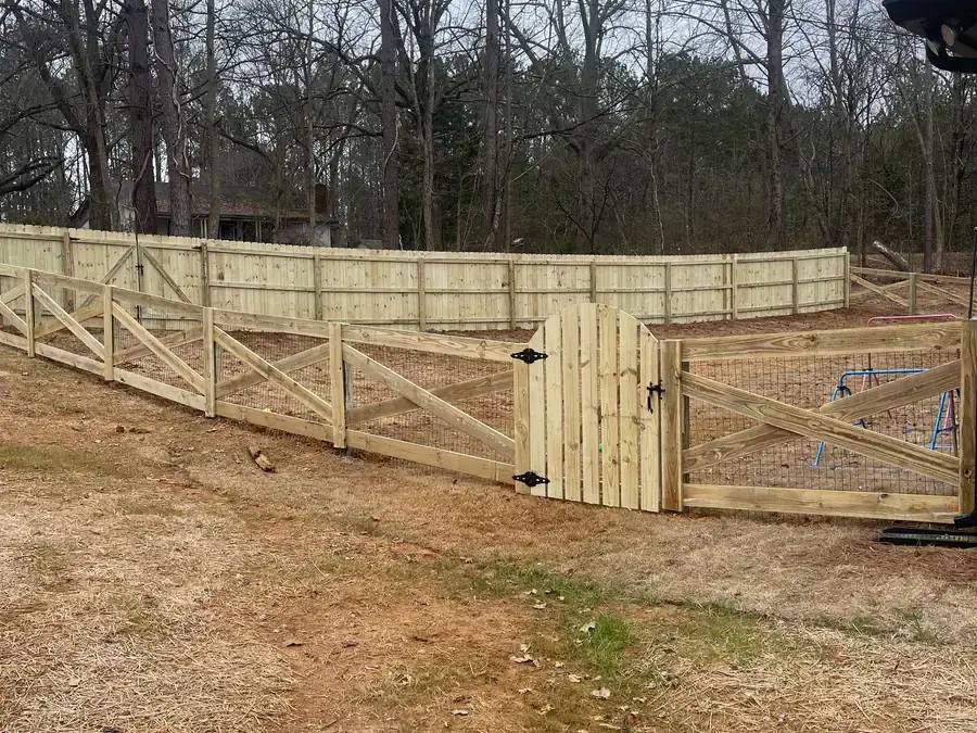 Crossbuck wood ranch fence with a matching double gate and welded wire behind the rails