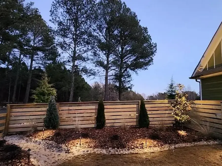 Horizontal slat wood fence beside a landscaped bed at the side of a house