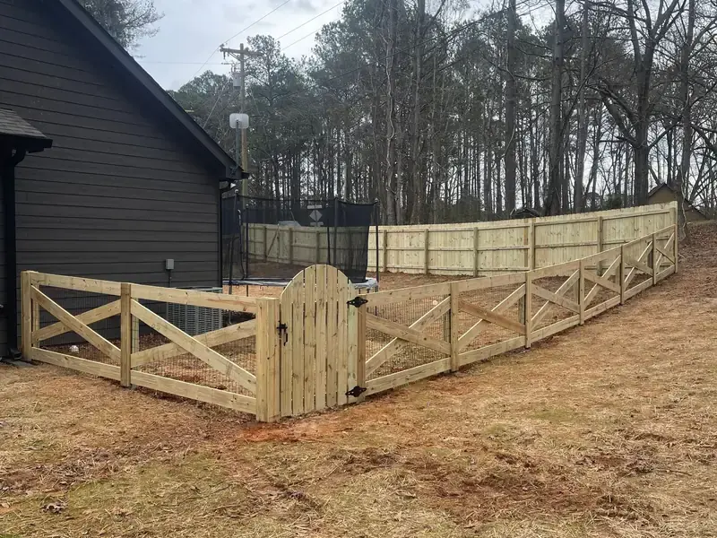 Crossbuck wood fence with an arched walk gate beside a dark grey house