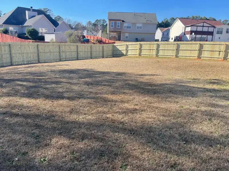 Wood privacy fence running along the back line of a suburban yard