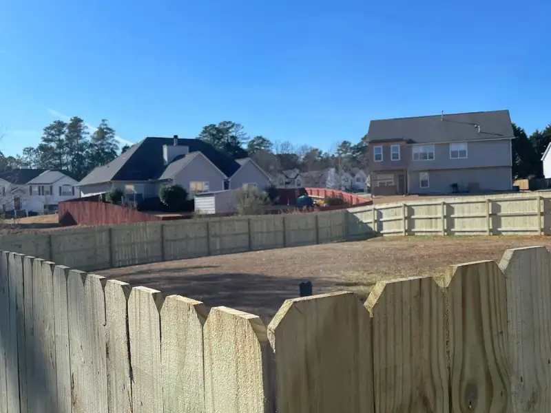 Dog ear wood privacy fence turning a corner at the edge of a back yard